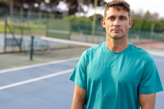 Portrait of caucasian male tennis player wearing green t shirt on outdoor court, copy space