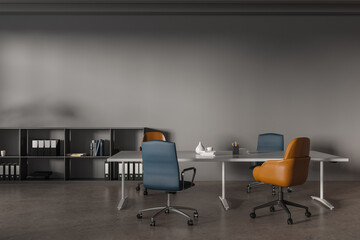 Grey coworking interior with a table and chairs, shelf and mockup wall