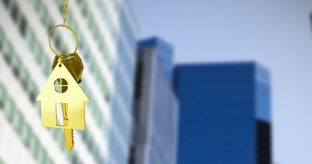 Image of golden house keys against blurred view of tall buildings