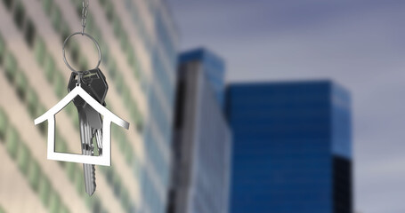 Image of hanging silver house keys against blurred view of tall buildings