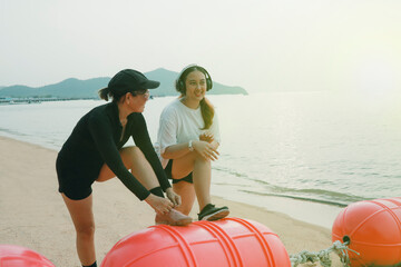 two asian woman stretching before exercise on sea beach