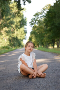 girl on the road, girl walks along a long road, road in summer, childhood, vacation and people concept - happy little girl walking on the road
