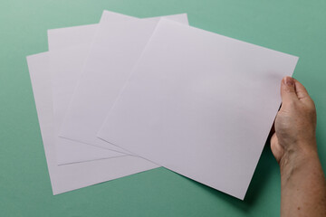 Hand of caucasian woman holding piece of paper over paper pieces with copy space on green background