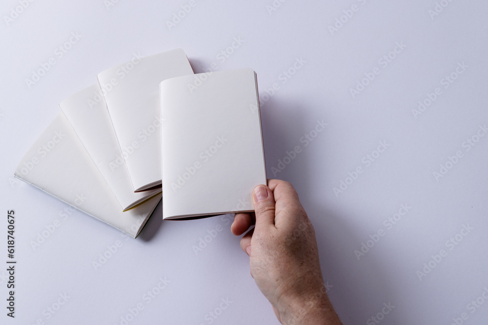 Poster Hand of caucasian woman notebook over other notebooks with copy space on white background