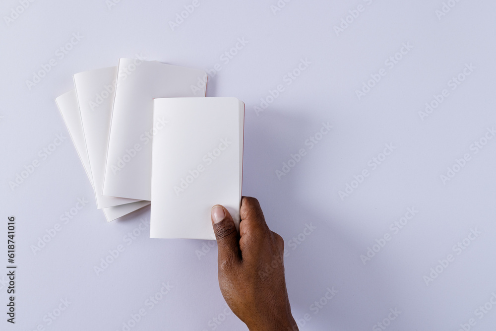 Poster hand of biracial man holding notebook over notebooks with copy space on white background