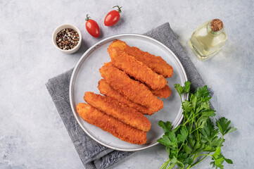 Chicken fillet sticks  fried on a plate with parsley on a light background with tomatoes and spices. Dietary and healthy food.