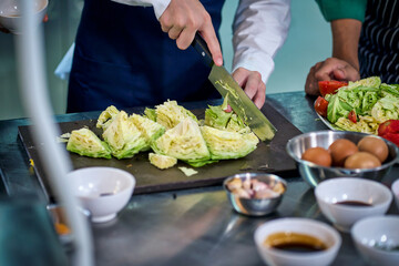 Chef assistant cutting fresh savoy cabbage in the kitchen for make a food
