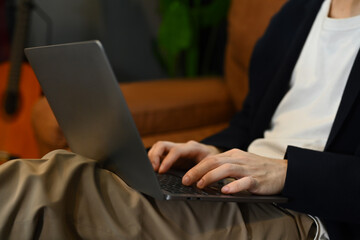 Cropped image of man hands typing on keyboard of laptop, working remotely, learning online, using internet banking