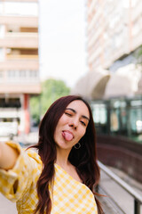 Woman shows her tongue while taking a selfie in the street