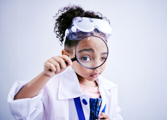 Child, magnifying glass and portrait of a scientist girl in studio with eye for scientific...