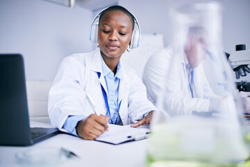 Research notes, music and a black woman in a lab studying healthcare and writing a report....
