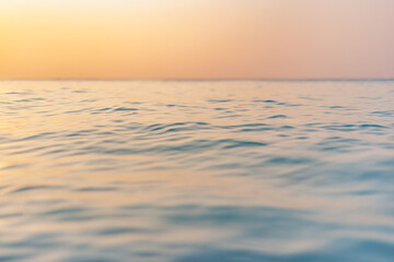 Fototapeta premium Sea wave closeup, low angle view, sunrise sunset sunlight. Idyllic Earth day seascape. Calm waves, golden orange sky horizon. Tranquil graphic illustration background. Minimal inspire ocean wallpaper