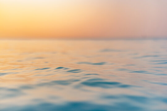 Sea wave closeup, low angle view, sunrise sunset sunlight. Idyllic Earth day seascape. Calm waves, golden orange sky horizon. Tranquil graphic illustration background. Minimal inspire ocean wallpaper