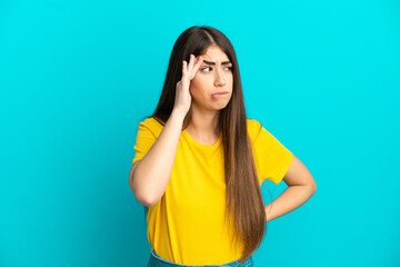 Young caucasian woman isolated on blue background with headache