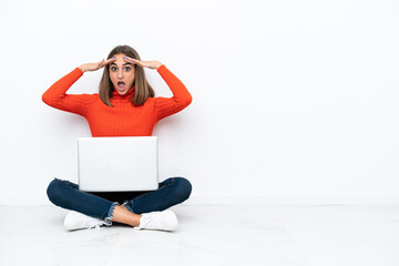 Obraz premium Young caucasian woman sitting on the floor with a laptop with surprise expression