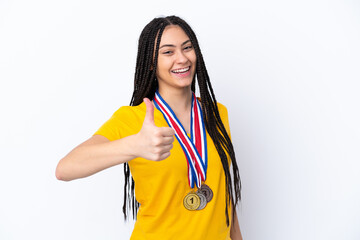 Teenager girl with braids and medals over isolated pink background with thumbs up because something good has happened