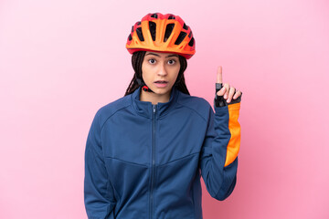 Teenager cyclist girl isolated on pink background thinking an idea pointing the finger up