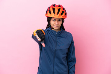 Teenager cyclist girl isolated on pink background showing thumb down with negative expression
