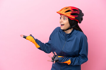 Teenager cyclist girl isolated on pink background with surprise expression while looking side - obrazy, fototapety, plakaty