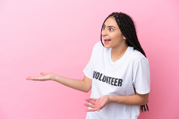 Teenager volunteer girl with braids isolated on pink background with surprise expression while...