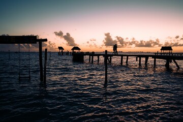Obraz premium Tranquil scene of a lake shoreline at sunset, with a dock stretching out into the water