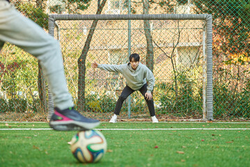 Two young male university students models playing with soccer ball on outdoor futsal field at...