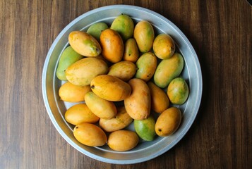 Naklejka na ściany i meble Mango fruits in a plate on wooden background 