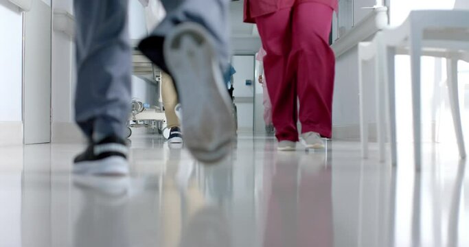 Low section of diverse doctors walking in corridor at hospital, slow motion