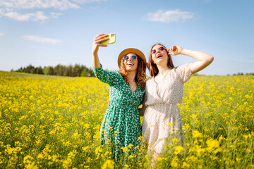 Selfie time.Two  Young woman takes a selfie while walking flowering field. Nature, vacation, relax and lifestyle. Summer landscape.