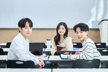 Fototapeta premium Male and female university students looking backwards talking or discussing during class or studying in a lecture hall at a Korean university in Asia.