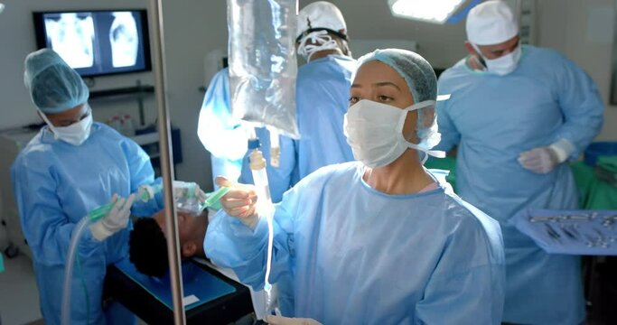 Diverse surgeons wearing surgical gowns, applying drip in operating theatre, slow motion