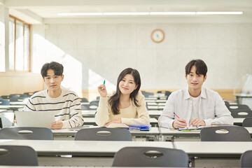 Three young Asian college students, both male and female, are in a classroom in South Korea where...