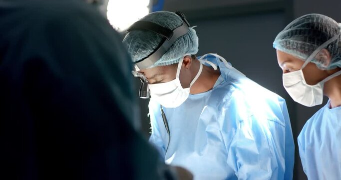 Diverse surgeons wearing surgical gowns operating on patient in operating theatre, slow motion