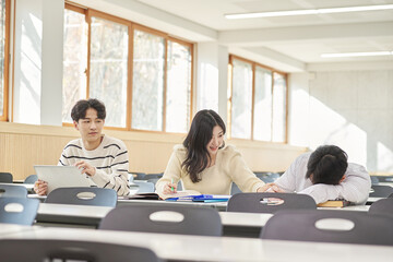 Fototapeta premium Three young Asian college students, both male and female, are in a classroom in South Korea where they are either teaching or studying