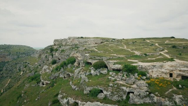 Drone shot of Murgia National Park with ruined stone buildings and caves on a hill