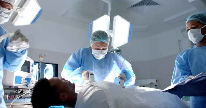 Diverse surgeons using defibrillator on patient in operating theatre, slow motion