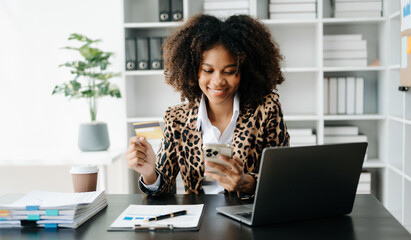 African Woman using smart phone for mobile payments online shopping,omni channel,sitting on table,virtual icons graphics interface screen
