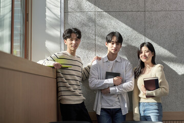 Model of a young male and female college student couple leaning against the wall of a university lecture hall in a light-filled room in South Korea, Asia. 