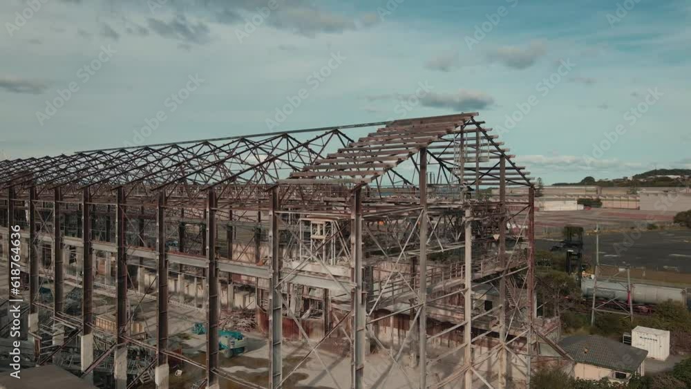 Aufkleber rotating drone view of industrial abandoned structures near storage towers and trees with cloudy sky