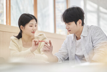 Colleague, friend, motivator, young male model comforting a distressed young female college student model sitting at a desk in a university classroom in Asia Korea.  