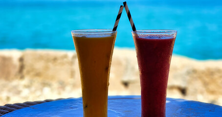 Two bright fruit juices on the beach on a sunny summer day