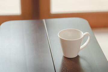 White ceramic cup for coffee on the wooden table, in breakfast time