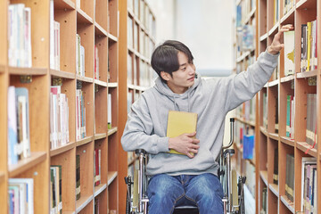 Asia South Korea university library bookcase in a wheelchair looking for a book on the shelf, physically handicapped young disabled male college student model
