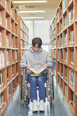 Asia South Korea university library bookcase in a wheelchair looking for a book on the shelf, physically handicapped young disabled male college student model