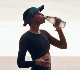 Drinking water, fitness and black woman by ocean for exercise, marathon training and running....