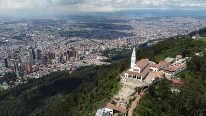 Fototapeta na wymiar Aerial view of a church on top of a green hill against the cityscape of Bogota, Venezuela
