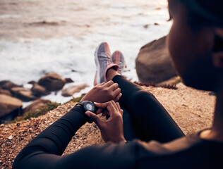 Relax, running and smart watch with hand of woman on rock for check, fitness tracker and heart rate. Workout, exercise and goal with closeup of female runner at beach for monitor, goals and time