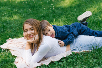 Little boy and his mom are relaxing in the park in the summer lying on the grass and having fun