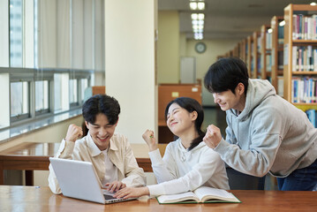 Fototapeta premium Two young college student man and woman couple model and solo male model looking at laptop and book together in library of Asian Korean university