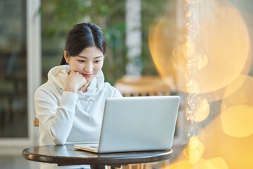 Young female college student model sitting at a cafe table in Asian Korea, listening to a lecture,...